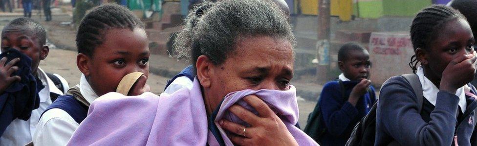 A woman and students cover themselves from tear gas during a demonstration of opposition supporters in Kenya - May 2016