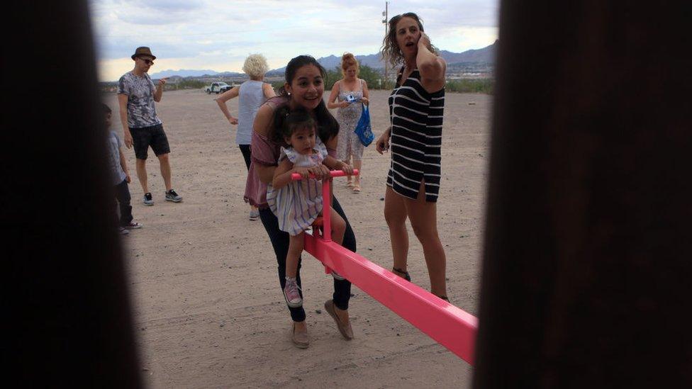 American and Mexican families play on seesaws over the Mexican border