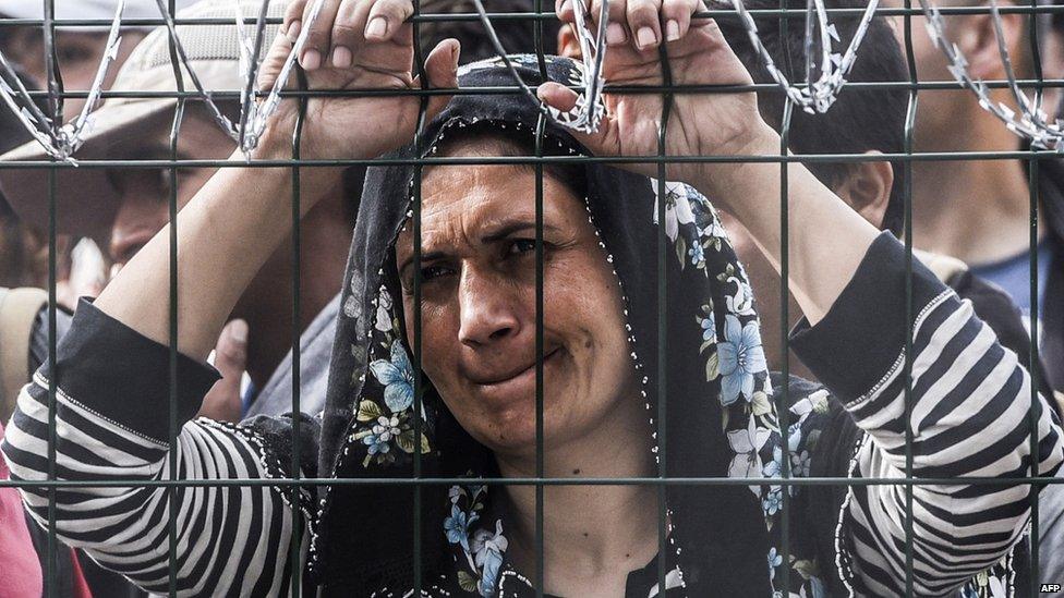 A refugee stands behind a fence at the Hungarian border with Serbia near the town of Horgos on 16 September 2015