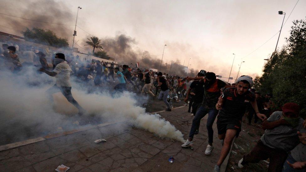 Demonstrators run away from tear gas in Baghdad