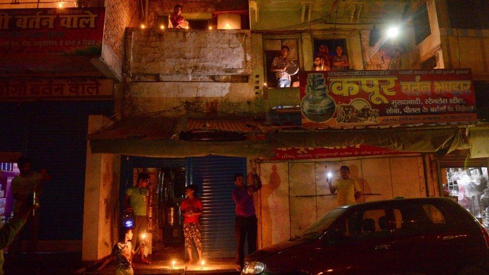 Residents light candles and turn on their mobile phone lights in India