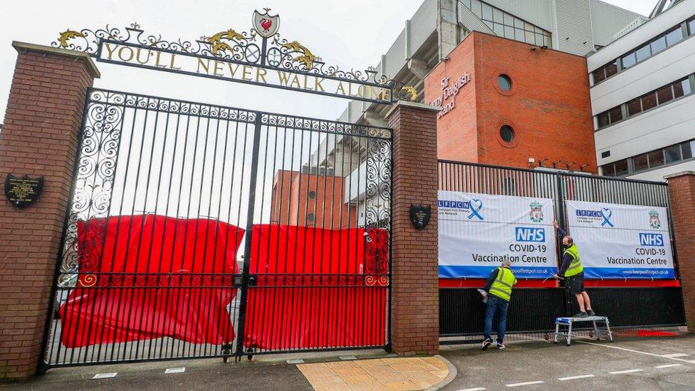 Men put up vaccination signage outside Anfield