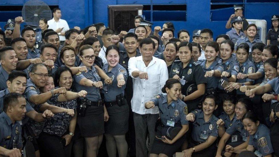 Philippines President Rodrigo Duterte (centre) poses for a picture with the Bureau of Jail and Penology Management (BJMP) personnel as he visits a detention cell of the BJMP located within Camp Bagong Diwa in Manila (19 October 2017)