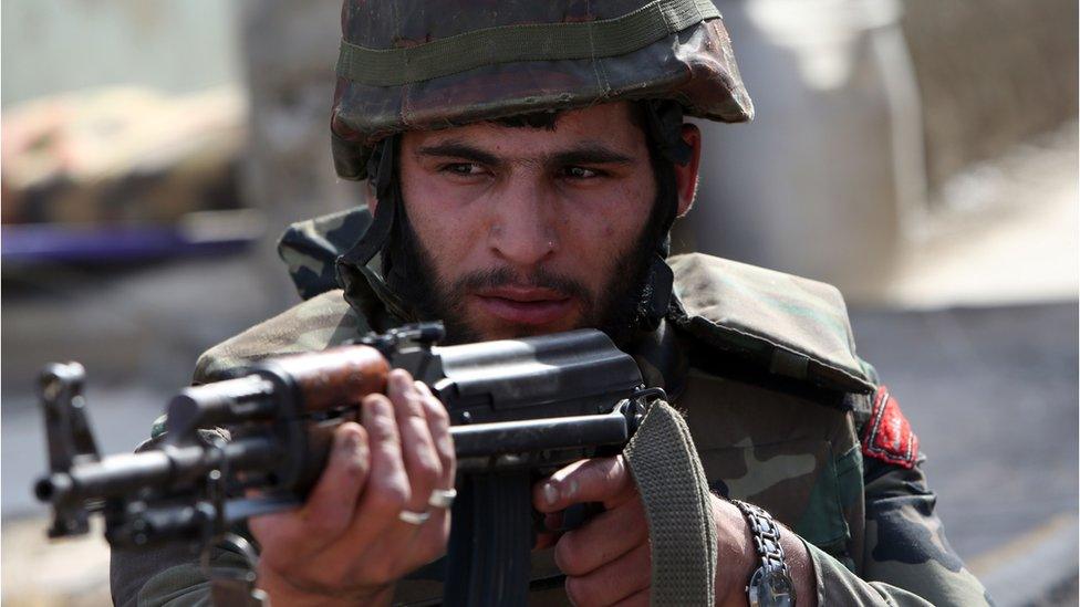 A Syrian army soldier aims his weapon during a battle against opposition fighters in the city of Qusayr