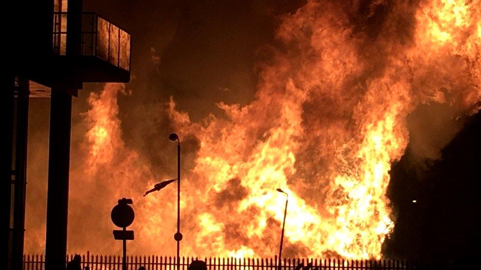 Flames a shown towering behind the apartment building's balconies