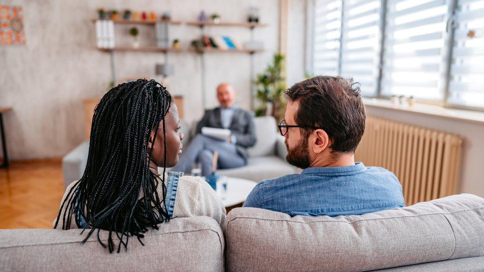 A couple sitting on a couch during a talking session with another person