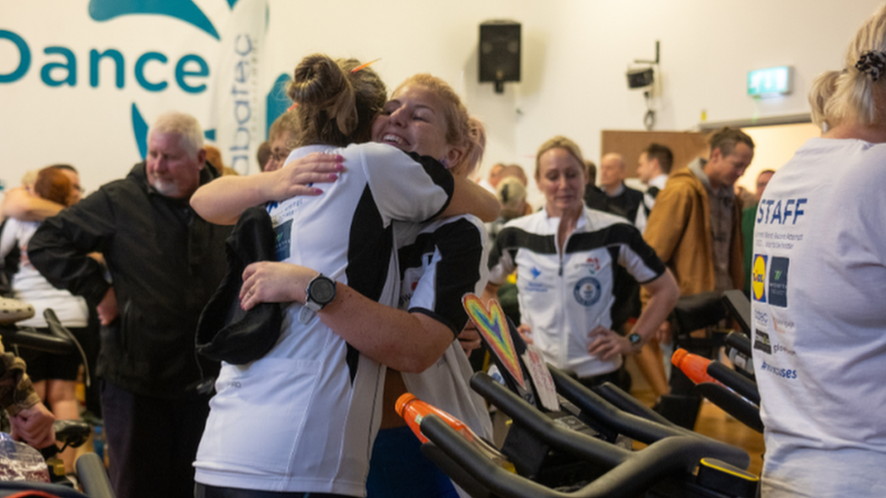 People hugging each other after riding on stationary bikes