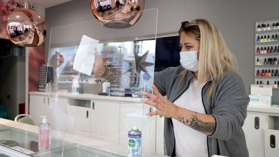 Shop owner wipes perspex screen