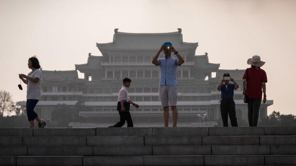 In a photo taken on 19 July 2017 tourists take photos before the Grand People's Study House on Kim Il-Sung square in Pyongyang