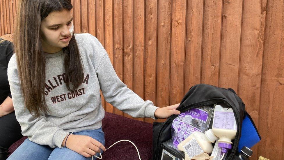 Halle with the bag she carries linked to a feeding tube