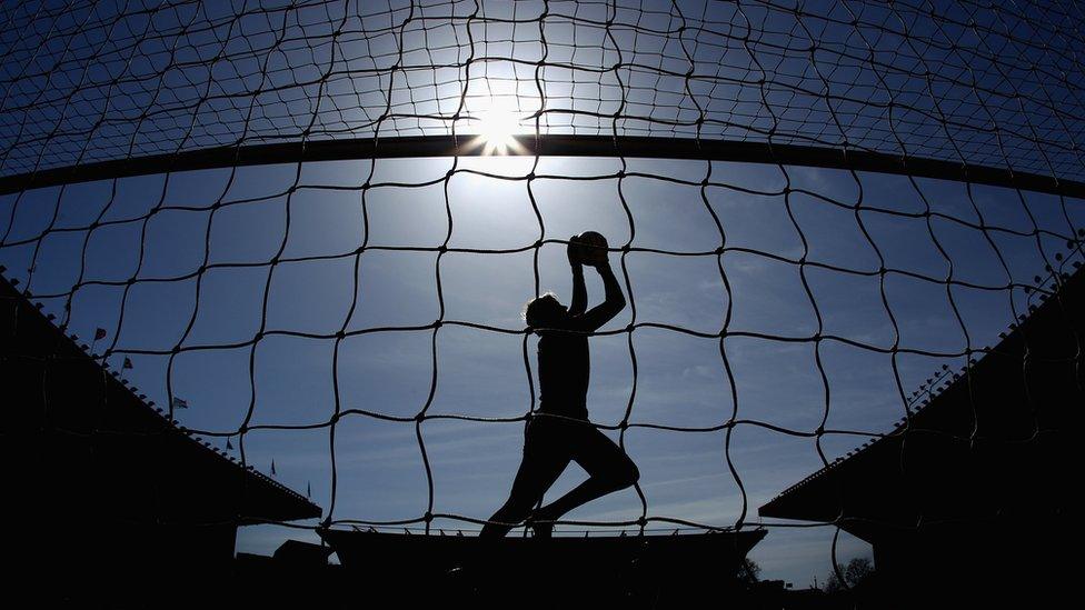 A football goalkeeper in silhouette