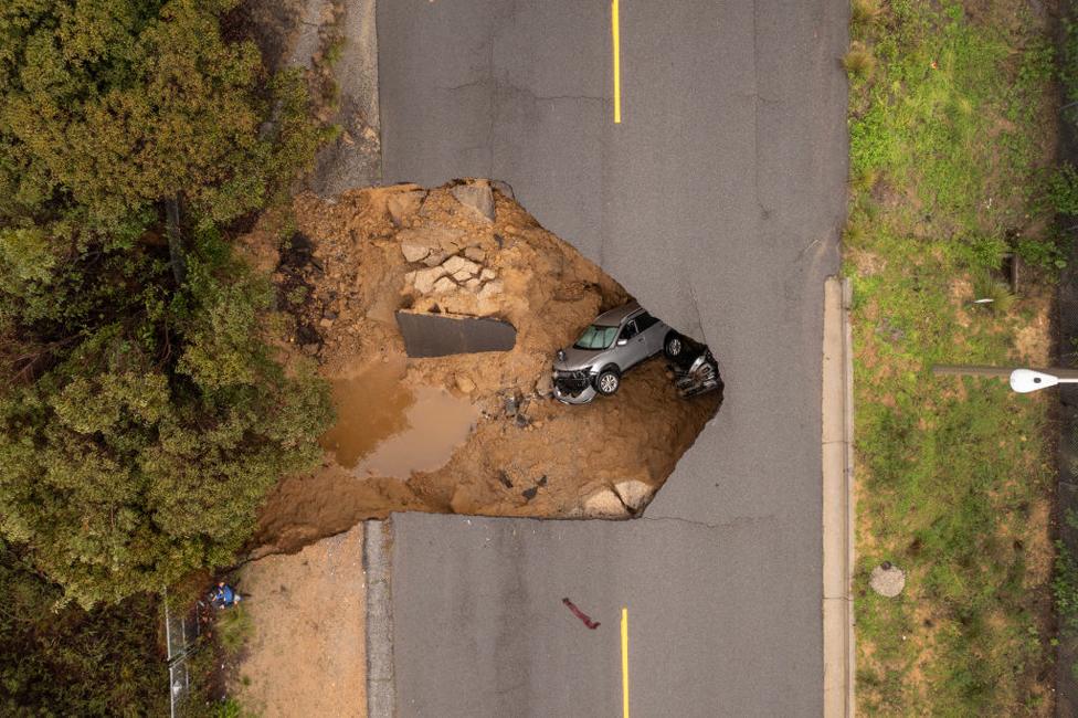 In an aerial view, a car and a pickup truck are seen inside a sinkhole on January 10, 2023 in Los Angeles, California.