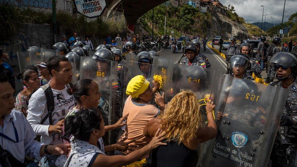 A group of people protest in front of members of the Bolivarian National Police (PNB) in Caracas, Venezuela, 28 December 2017.