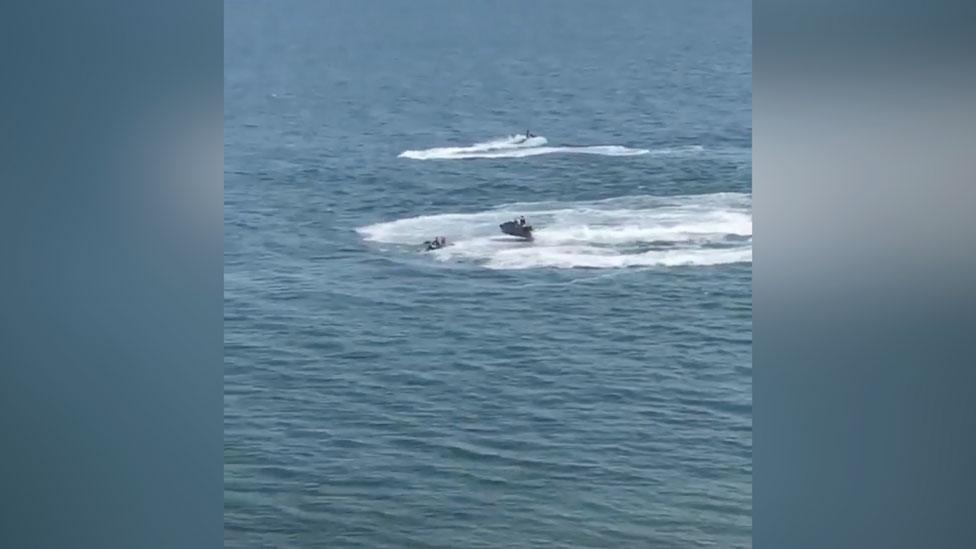 Water bike users repeatedly circled next to two paddleboarders, sending waves over them