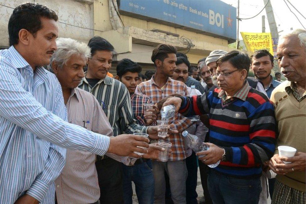 Indian volunteers distribute water to people, waiting in a queue to deposit and exchange 500 and 1000 rupee notes, outside a bank in Amritsar on November 16, 2016.