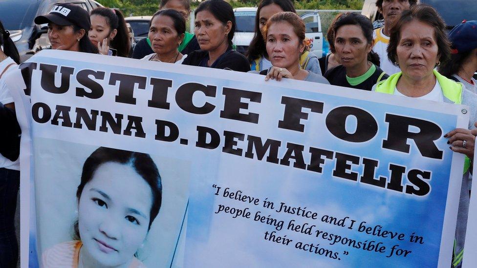 Residents display placards as they wait for the arrival of the body of Joanna Demafelis, a Filipina domestic helper who was killed and found inside a freezer in Kuwait, in her hometown in Iloilo province in the Philippines February 17, 2018