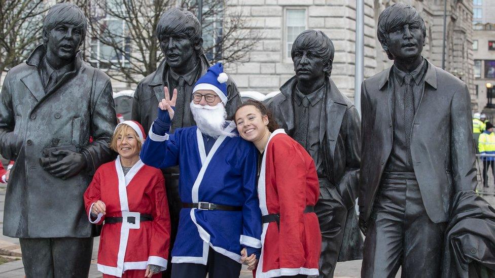 runners pose in front of the beatles statue