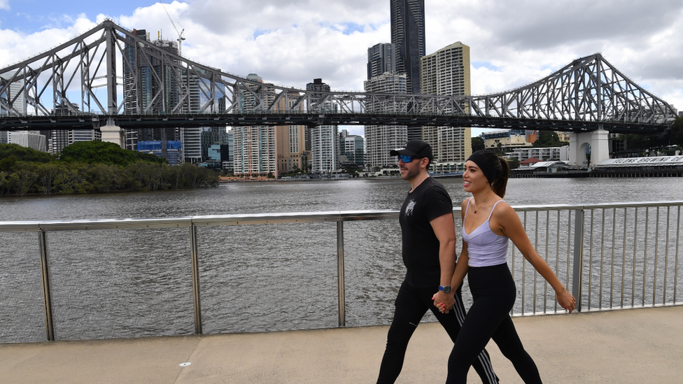 A couple walk next to Brisbane River during lockdown