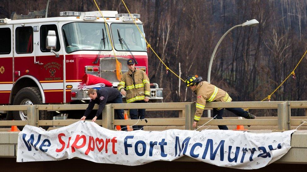 Fort McMurray firefighters fix a sign that reads "We Support Fort McMurray" on an overpass above Memorial Dr. in Fort McMurray, Alberta, Canada 1 June 2016.