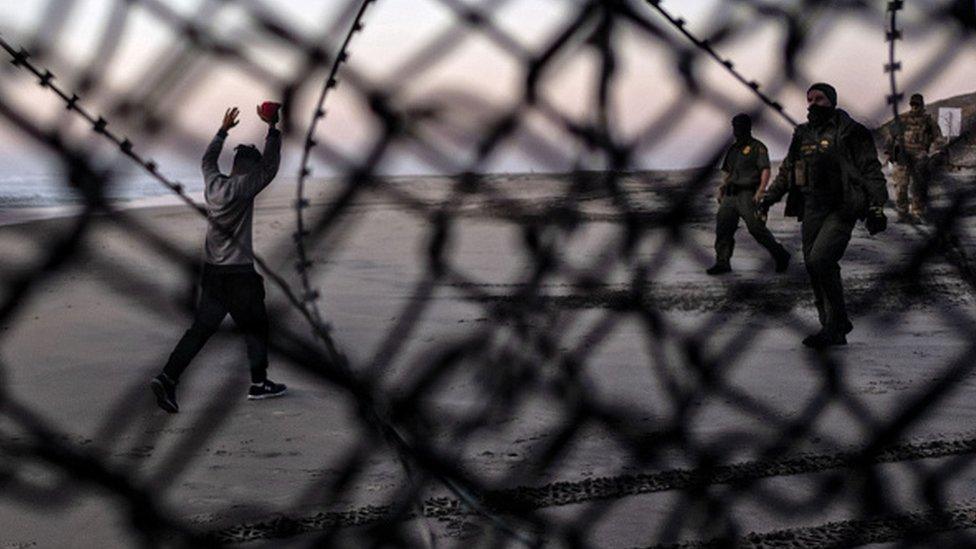 A migrant surrenders to US border patrol officers