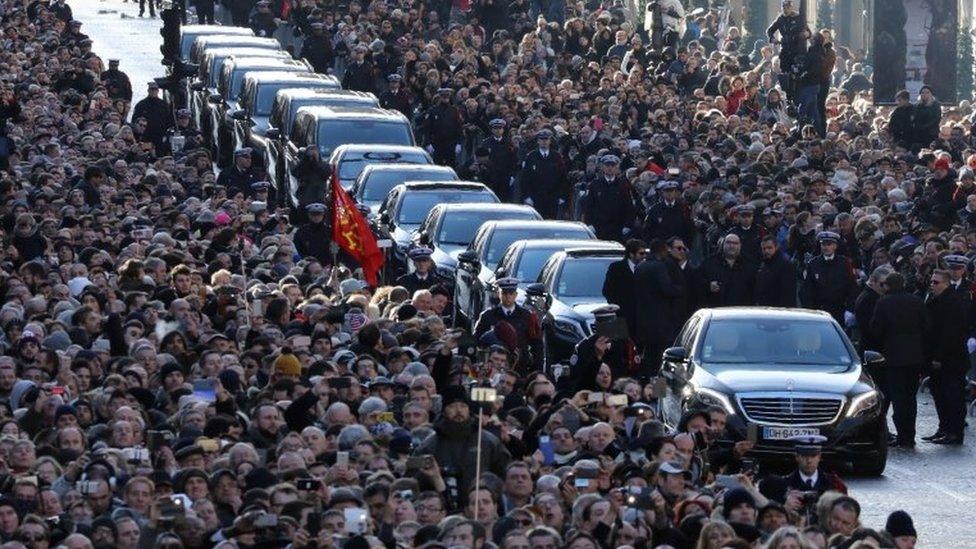 People gather outside the Madeleine church in Paris for the funeral ceremony of the late French singer Johnny Hallyday, 9 December 2017