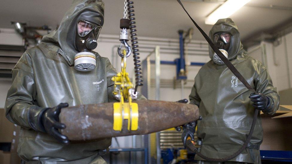 Workers in protective clothing unload a dummy shell during a media day at the GEKA facility in Munster, Germany, on 5 March 2014