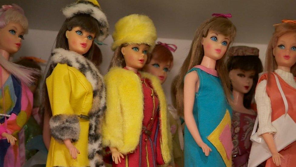 Barbies on a shelf with colourful outfits