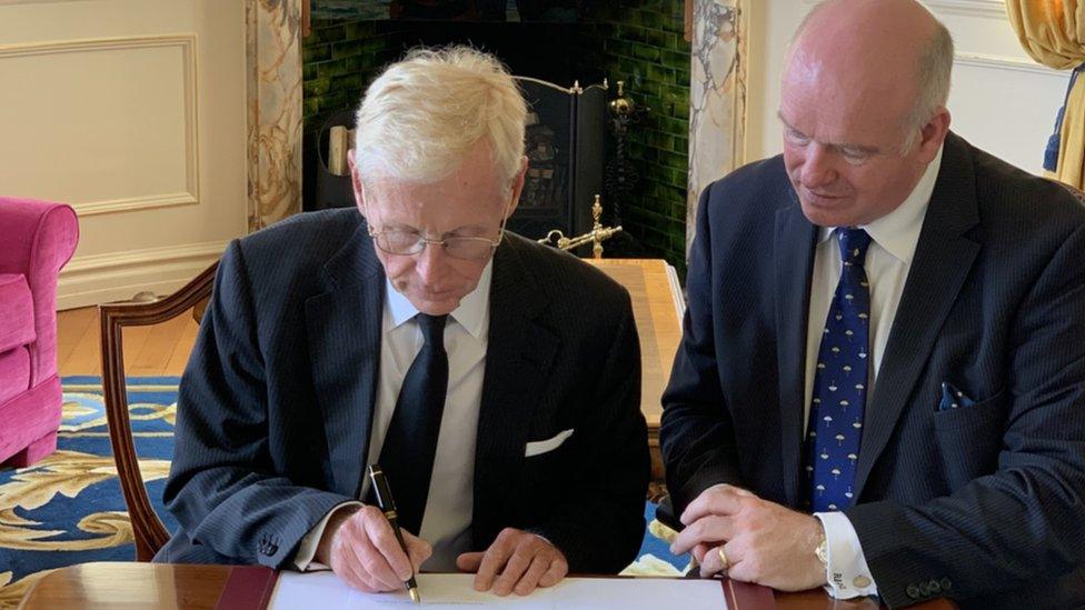 Lt Governor Sir Richard Gozney signing the revocation watched by chief minister Howard Quayle