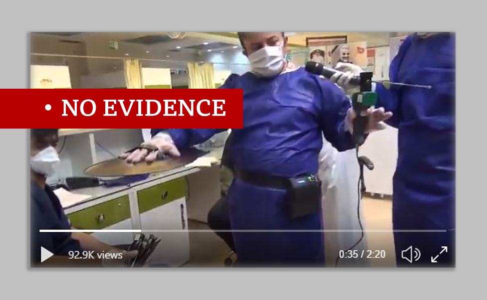 Screenshot of video showing the Iranian device which claims to be able to detect coronavirus. Man in protective clothing holds the device in left hand and cymbal in the other towards the patient.