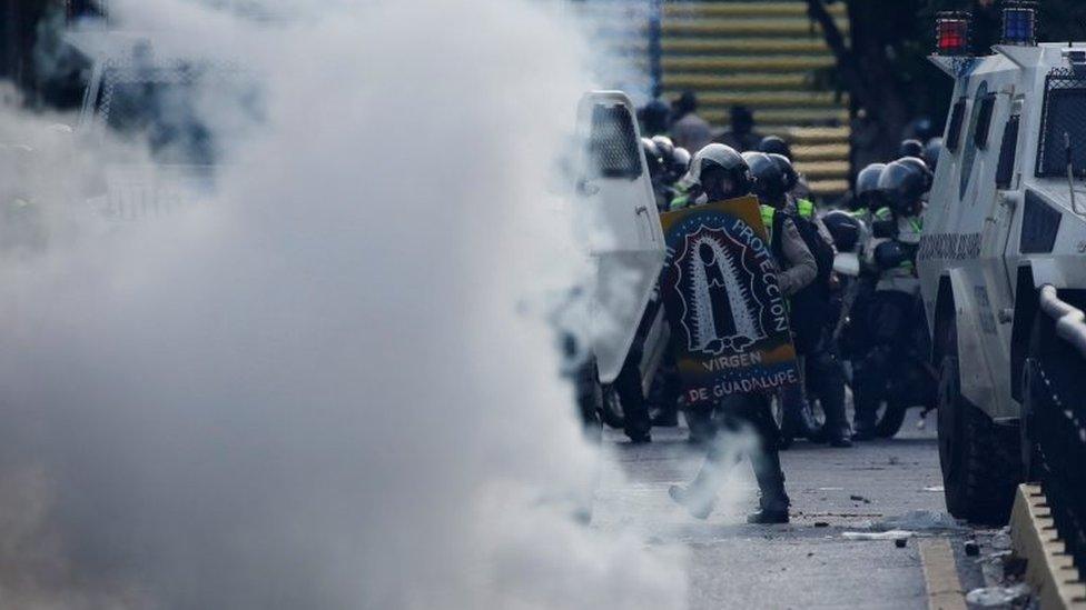 A riot police officer holds a makeshift shield with an image of Our Lady of Guadalupe during clashes with opposition supporters at a rally against Venezuela's President Nicolas Maduro in Caracas, Venezuela 20 May 2017.