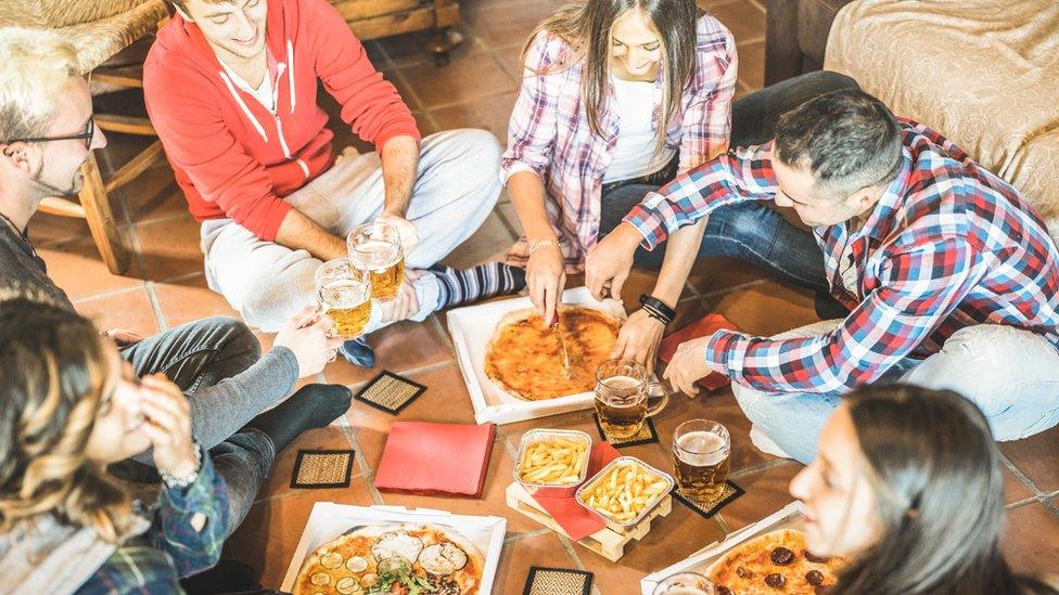 Young people eating pizza on the floor