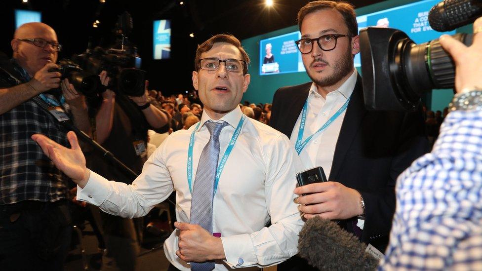 Simon Brodkin being led out of the conference hall