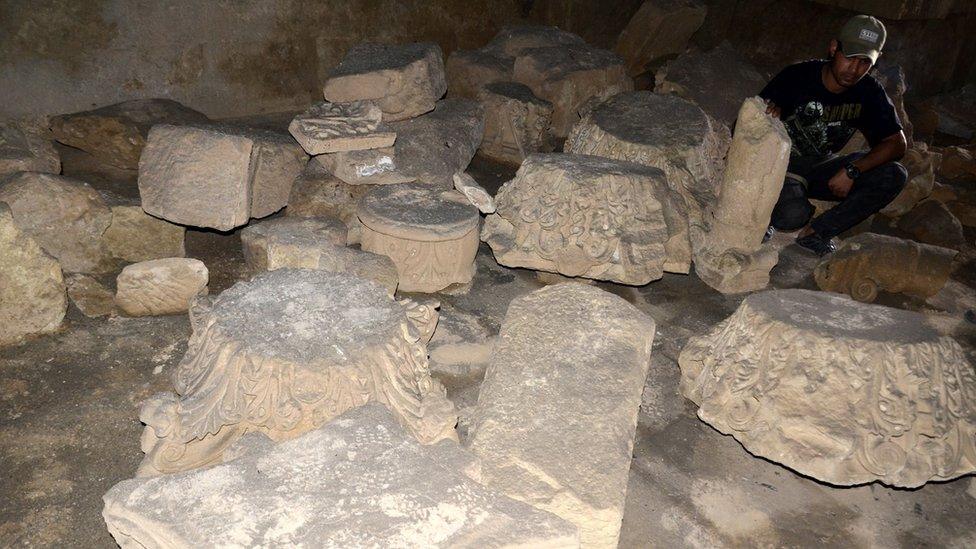 Member of the paramilitary Popular Mobilisation force inspects damaged artefacts at the ancient city of Hatra in Iraq (28 April 2017)