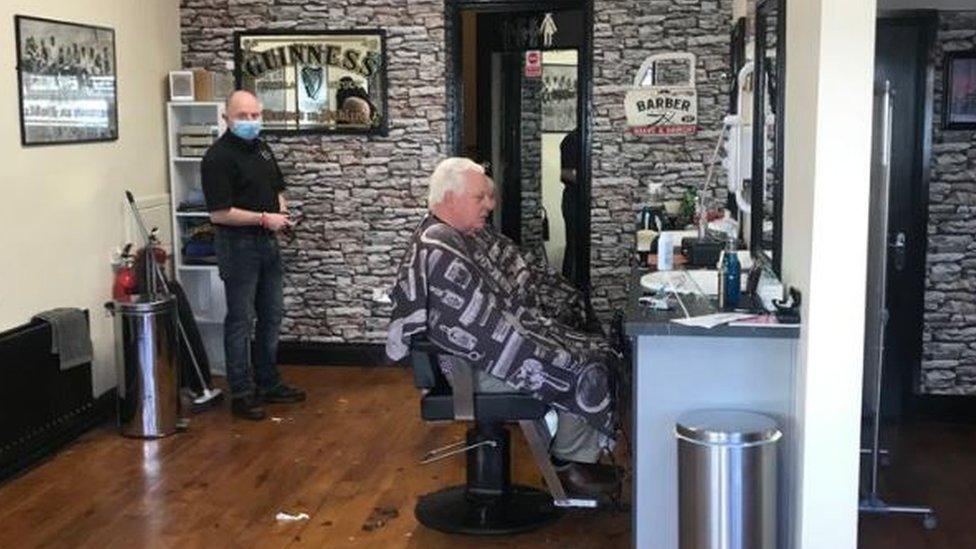 A man with white hair siting in the barber's chair in Paddy Burns' barber shop in Londonderry