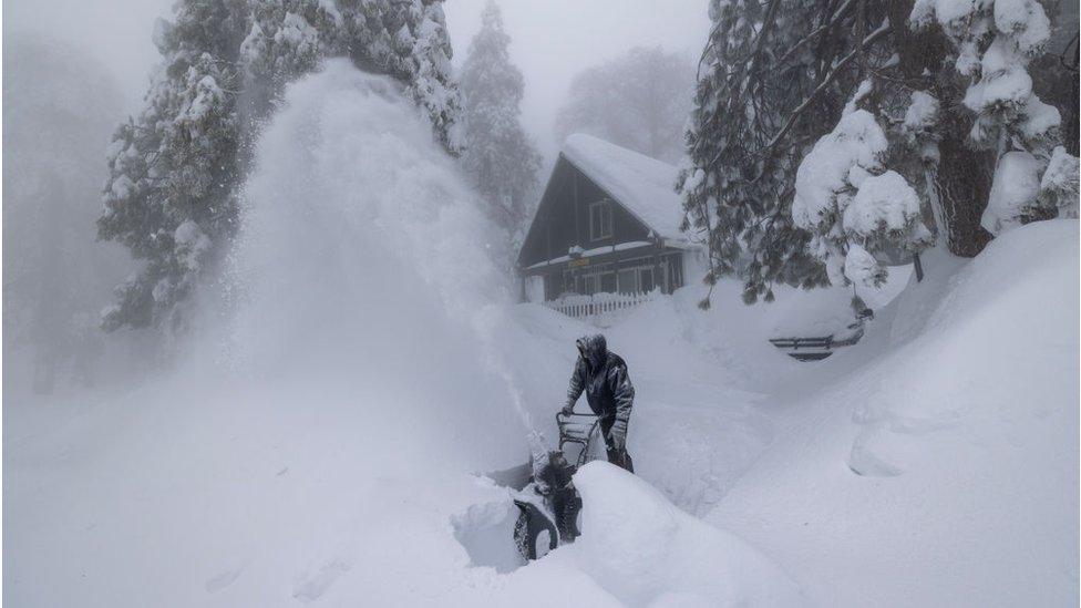 A Running Springs, California resident clears snow outside his home