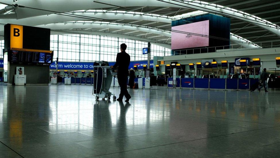 Cleaner pushes trolley through deserted terminal