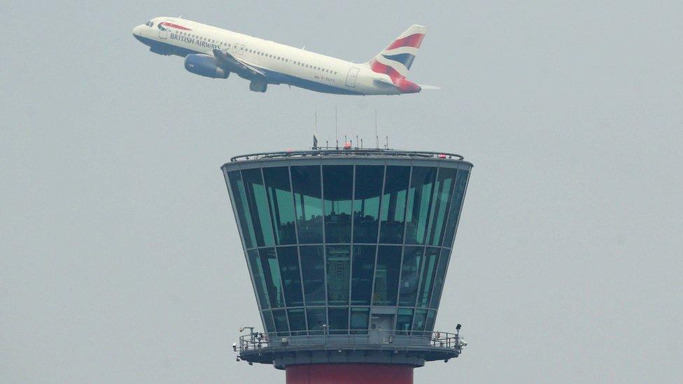 A British Airways plane takes off above the control tower at Heathrow Airport