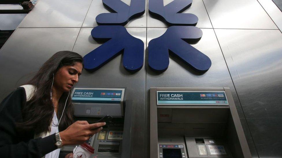 Woman walking past RBS logo