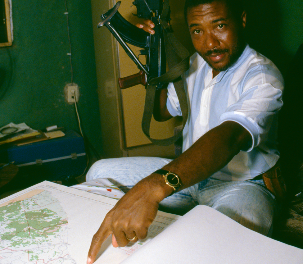 Charles Taylor holding a gun and pointing at a map in 1989, the year he launched a rebellion in Liberia