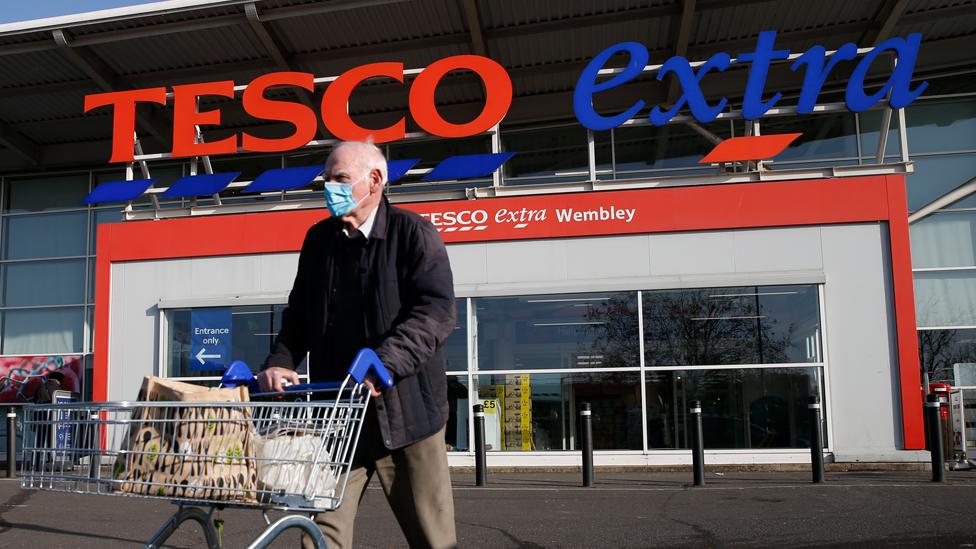 A shopper wheels a trolley out of a Tesco Extra supermarket in Wembley on 7 November 2020