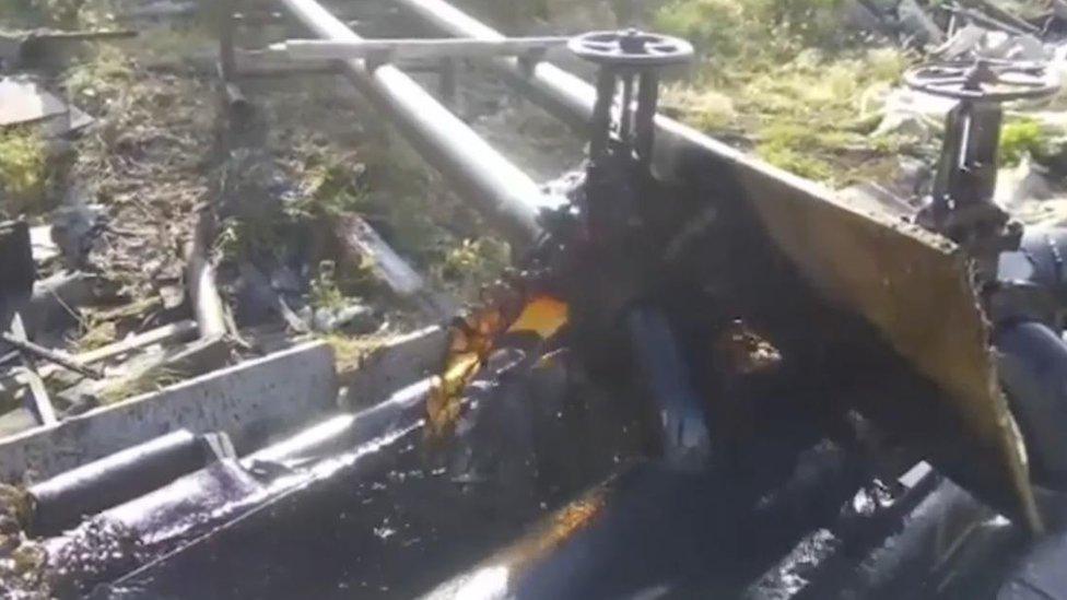 A still of oil gushing from a leaking pipe in Chersky