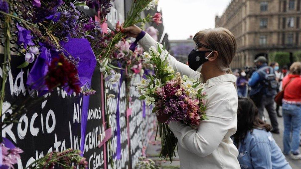 A woman places flowers beside the names of victims of femicide in Mexico on fences placed outside the National Palace ahead of a Women"s Day protest in Mexico City, Mexico March 7, 2021