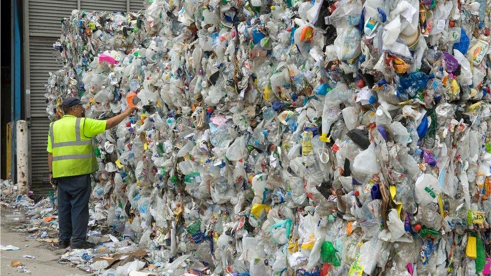 A man examines bailed waste