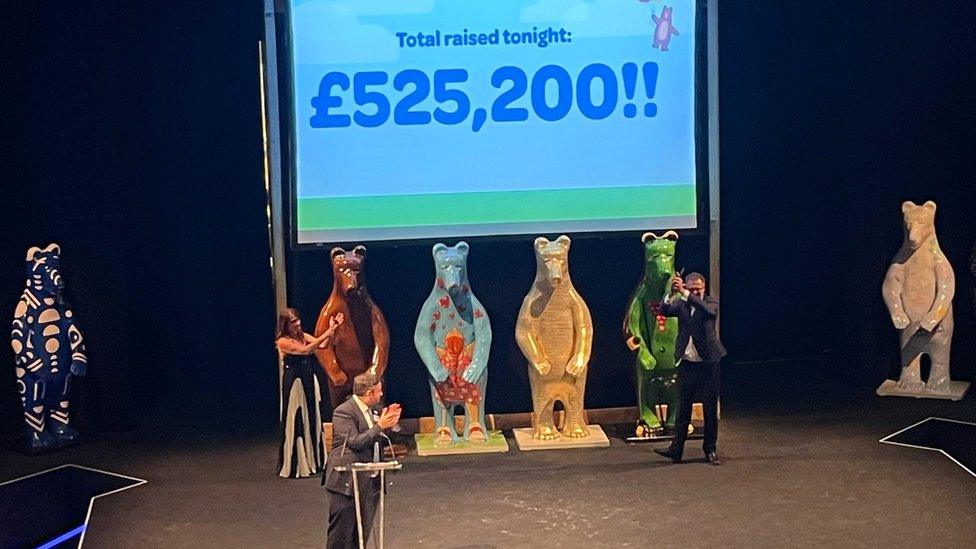 People standing in front of bear statues at a charity auction