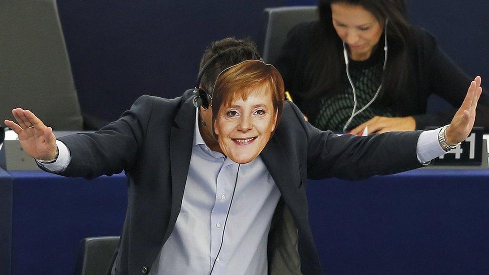 Italian Member of the European Parliament Gianluca Buonanno gestures as he wears a mask depicting German Chancellor Angela Merkel