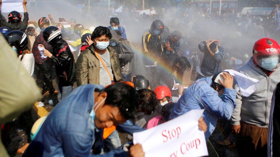 Police fire a water cannon at protesters