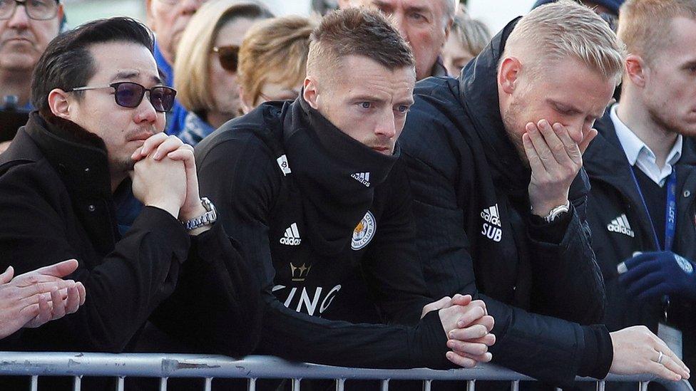 Khun Aiyawatt Srivaddhanaprabha, son of Leicester Citys owner, Jamie Vardy and Kasper Schmeichel look at tributes left for Vichai and four other people