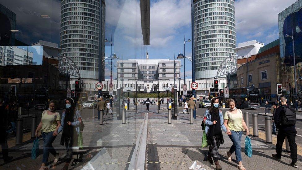 People wearing face masks pass near the Bullring in Birmingham