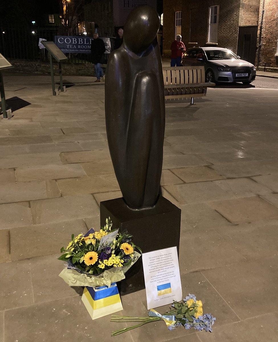 Flowers for solidarity of people in Ukraine left by a peace sculpture in King's Lynn