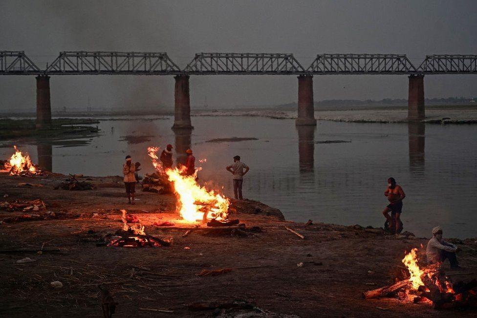 Funeral pyres are lit by the Ganges in Allahabad, where bodies have been washing downstream for days